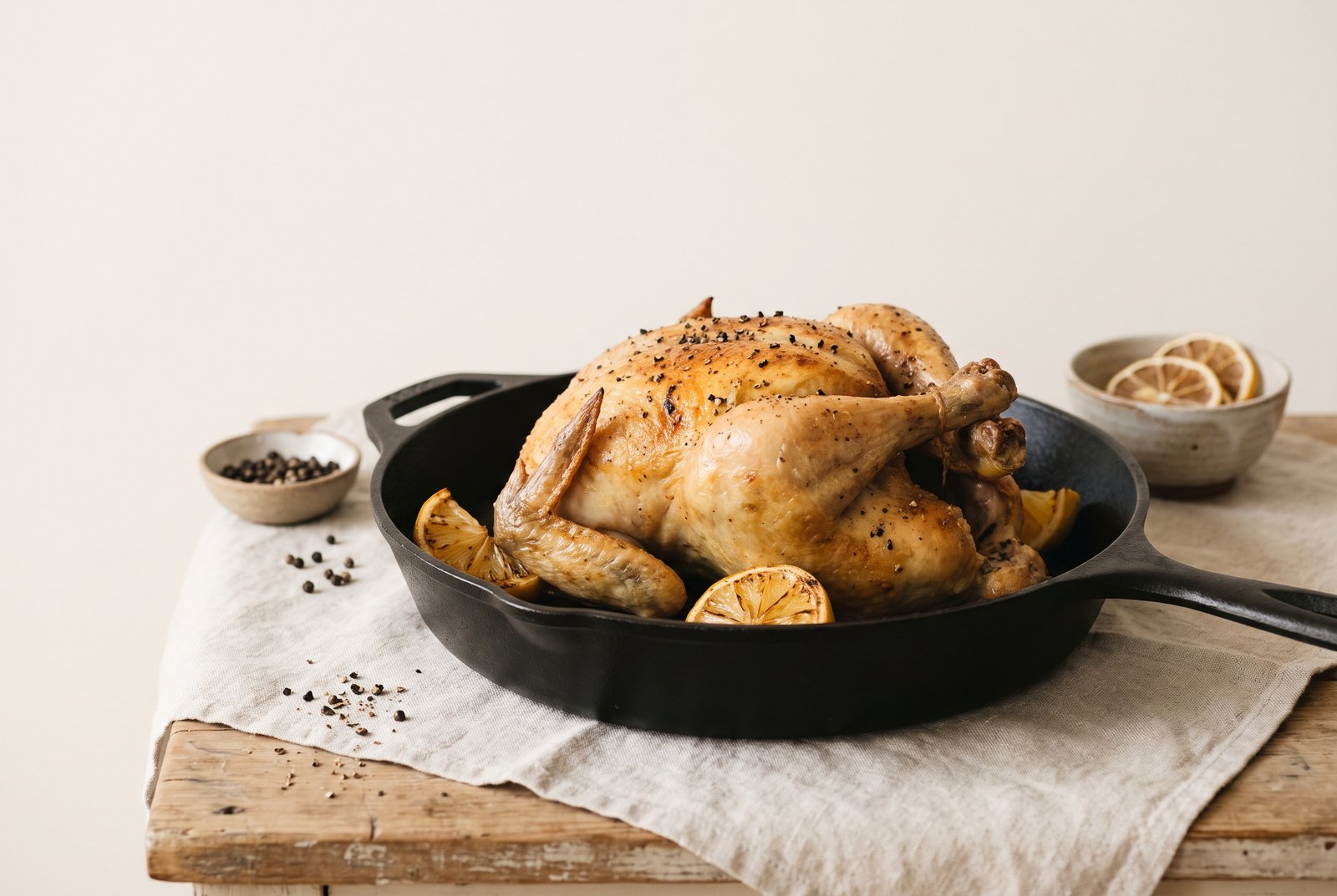 Golden lemon black pepper chicken in a skillet with lemon wedges and cracked pepper