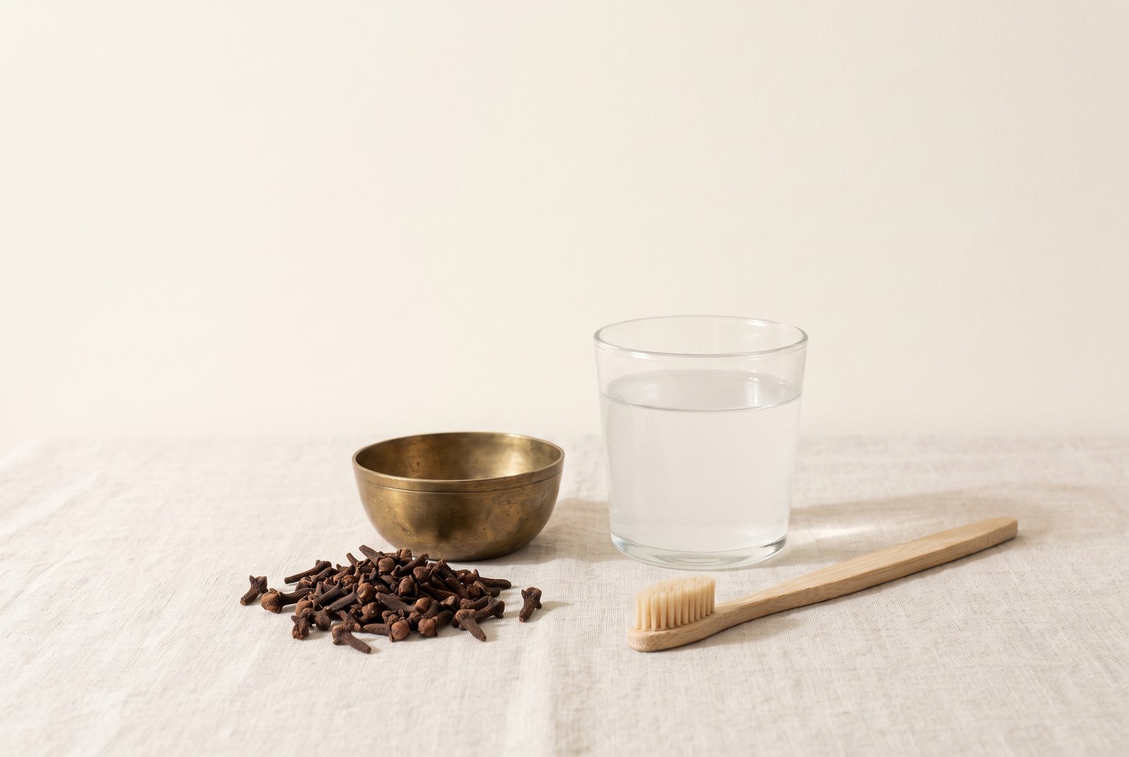 Whole cloves and a glass of salt water beside a soft toothbrush